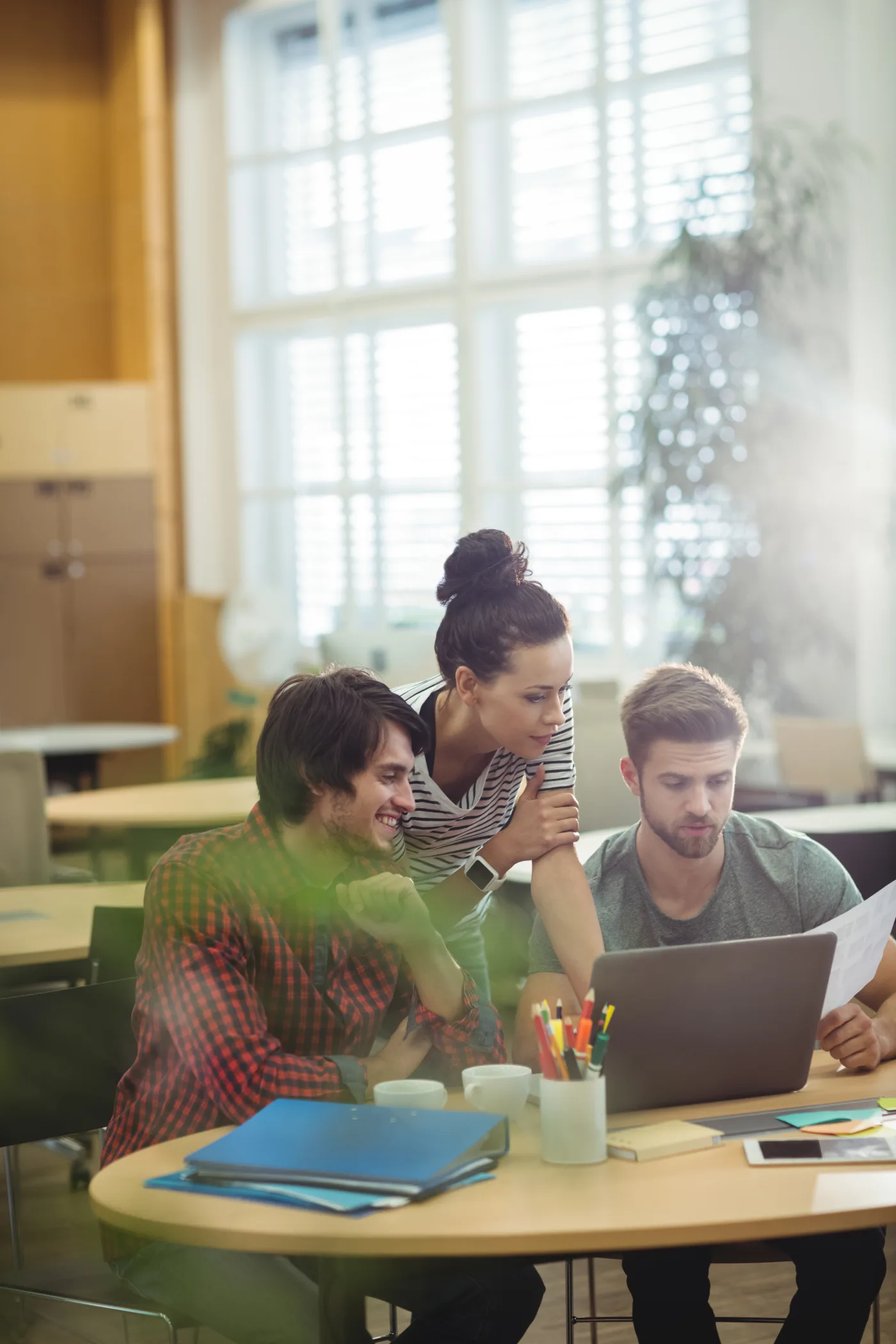 Tre persone al lavoro insieme davanti a un laptop in uno spazio formativo